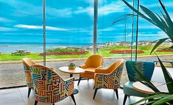 a modern living room with a view of the ocean , featuring colorful furniture and a potted plant at Bayview Hotel
