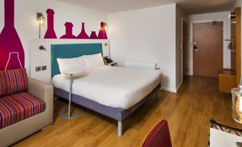 a modern hotel room with wooden floors , white walls , and a bed dressed in white sheets at Ibis Styles Barnsley
