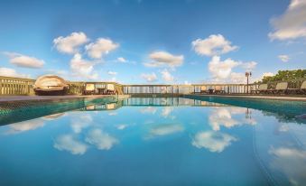 a large swimming pool with a clear blue sky and clouds reflected in its surface at Lime Tree Bay Resort