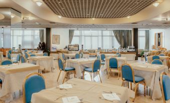 a large , empty banquet hall with blue chairs and tables set up for a meal at Hotel Minerva