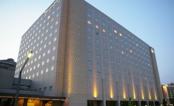 a tall hotel building with many windows and lights on , set against a blue sky at Oriental Hotel Tokyo Bay