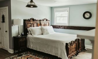 a cozy bedroom with a wooden bed , white sheets , and a rug on the floor at The Bond 1835