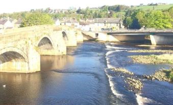 a stone bridge spanning a river , with several people walking on it and enjoying the view at Anchor Hotel