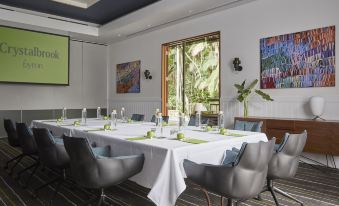 a dining room with a long table covered in white tablecloths , surrounded by several chairs at Crystalbrook Byron