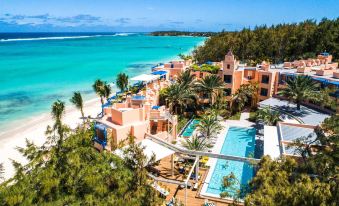 a tropical resort with multiple buildings and palm trees , set against the backdrop of a clear blue ocean at Salt of Palmar, Mauritius