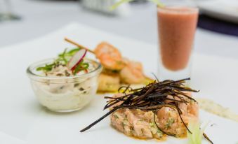 a plate of food , including shrimp and vegetables , next to a smoothie with chocolate sticks at Peduase Valley Resort