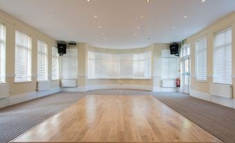 a large , empty room with wooden floors and white walls is shown in the image at Healing Manor Hotel