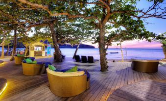 a wooden deck overlooking a body of water , with several lounge chairs and umbrellas placed around the area at Mantaray Island Resort