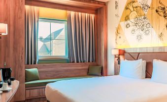 a large bed with white sheets is in a room with a window and a bench at Mercure HAN Sur Lesse