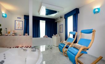 a luxurious bathroom with a large bathtub , two blue reclining chairs , and a television mounted on the wall at Hotel Centrale