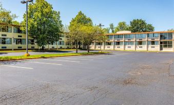 a large building with a parking lot in front of it , surrounded by trees and grass at Colony Motel Jamestown