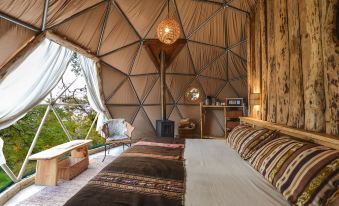 a cozy bedroom with a bed , a chair , and a stove in a geodesic dome - like structure at Ecocamp Patagonia