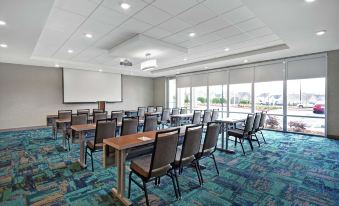 a conference room with rows of chairs arranged in a semicircle , and a projector on the wall at Home2 Suites by Hilton Lawrenceville Atlanta Sugarloaf