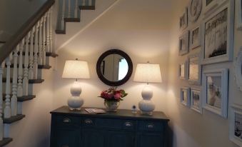 a hallway with a round mirror hanging on the wall , surrounded by a blue dresser and two lamps at Devils Lake Inn