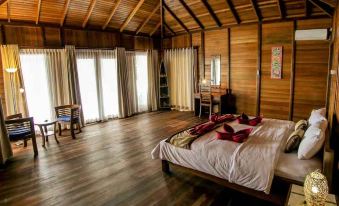 a large bedroom with wooden floors and walls , featuring a bed with red and white bedding at Sali Bay Resort