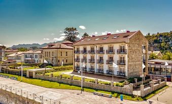 a large , three - story building with a curved roof and balconies is situated on a grassy area near a water body at Hotel Don Pepe
