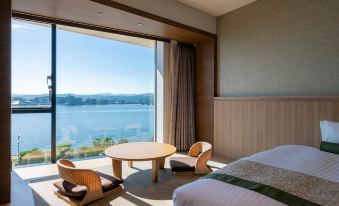 a hotel room with a large window overlooking a body of water , providing a scenic view at Hotel Ichibata