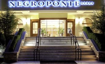 "the entrance of a hotel called "" gegroponte "" with its name displayed in blue neon letters" at Negroponte Resort Eretria