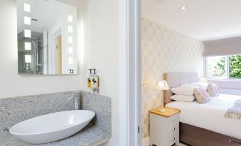 a modern bathroom with a marble countertop and white sink , connected to a bedroom with a bed and nightstand at The Orange Tree Thornham