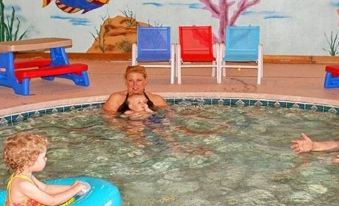 a woman and two children are in a swimming pool , with the woman in the water and the child sitting on a bench at Scandinavian Lodge
