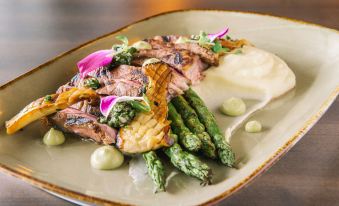 a plate of food on a dining table , with a steak and asparagus covered in sauce at The Brunswick Hotel