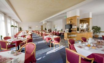 a large dining room with multiple tables and chairs arranged for a group of people to enjoy a meal together at Fairway Hotel