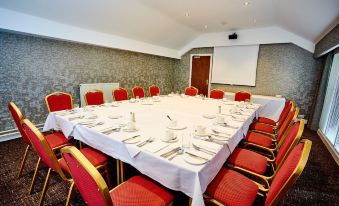 a conference room set up for a meeting with a large table in the center , surrounded by chairs at Abbotsford Hotel