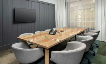 a conference room with a wooden table , chairs , and a phone on the table , surrounded by curtains and a window at Canopy by Hilton Ithaca Downtown