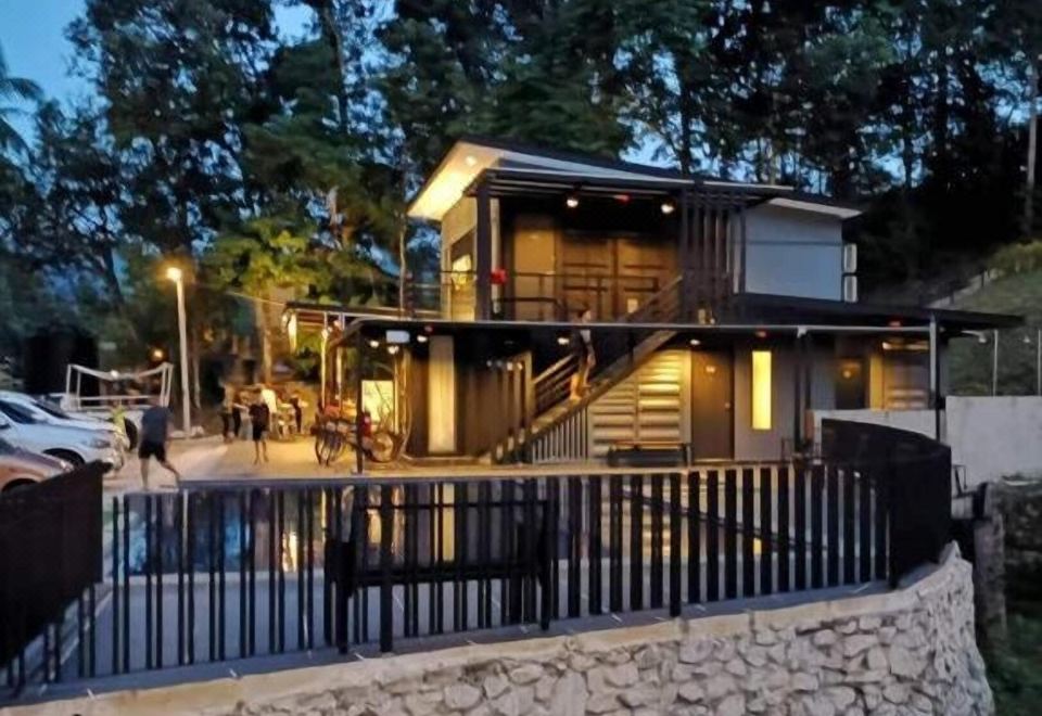 a large house surrounded by trees , with a pool in front of it , illuminated at night at Casa Hill Resort