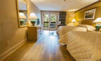 a cozy hotel room with wooden floors , two beds , and various decorative items , including a dresser , lamps , and a mirror at Carter Caves State Resort Park