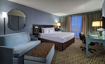 a modern hotel room with a large bed , couch , and desk , along with curtains and a window view of the city at Crowne Plaza Lombard Downers Grove