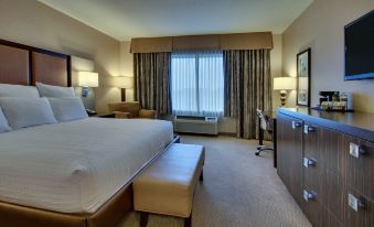 a hotel room with a large bed , a desk , and a window overlooking the city at The Inn at Charles Town / Hollywood Casino