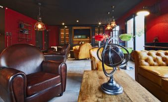 a cozy living room with red walls , wooden floors , and various seating options including leather chairs and a leather couch at Kyriad Lille Est - Hem