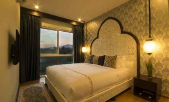 a large bed with a white headboard is in a room with a window and a mountain view at Palette the Grand Morocc Hotel