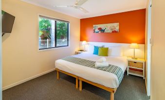 a bedroom with a large bed , orange walls , and two lamps on either side of the bed at Ingenia Holidays South West Rocks