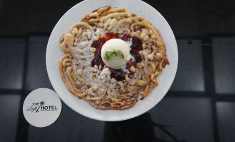 a white plate with a waffle topped with ice cream and berries , sitting on a dining table at The Loft Hotel, Siliguri
