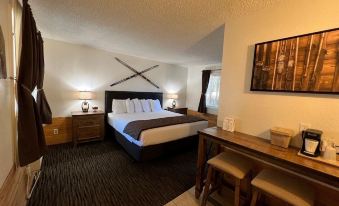 a large bed with white linens is in a room with a wooden table and chairs at Shasta Inn