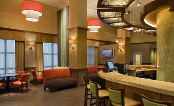 a modern , well - lit bar area with various seating options and a bar area with stools at Hyatt Place Saratoga Malta