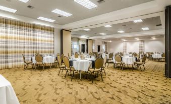 a large , well - lit banquet hall with several round tables and chairs arranged for a formal event at The Inn at GIG Harbor