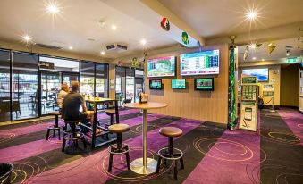 a modern restaurant with purple walls , wooden tables , and stools , along with large screens on the wall at Nightcap at Glengala Hotel