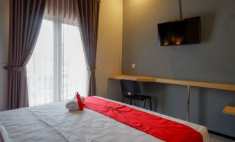 a hotel room with a comfortable bed , a television , and a window overlooking the city at RedDoorz Syariah @ Jalan Sultan Agung Tegal
