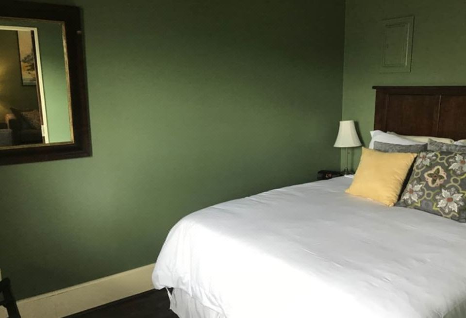 a bed with white sheets and yellow pillows is in a room with green walls at Lofts on Main