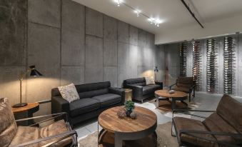 a modern living room with a large black leather couch , wooden coffee table , and multiple chairs at Wine Stone Inn
