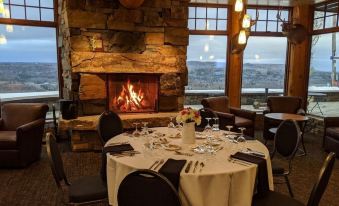 a dining room with a round table set for a meal , surrounded by chairs and a fireplace at Mont du Lac Resort