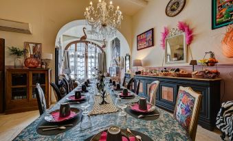 a long dining table is set with plates , cups , and utensils in a room with a chandelier at Hotel des Artistes