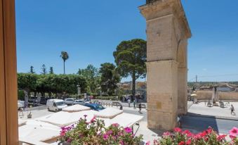 a large stone column with flowers growing on it , situated in the middle of a city square at Hotel Flora