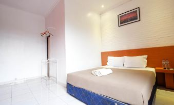 a bed with a blue headboard and white pillows is in a room with a white tile floor at Griya Ayem