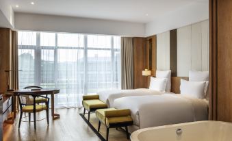 a modern hotel room with two beds , a bathtub , and a dining table , all arranged in the spacious space at Pullman Changbaishan Resort