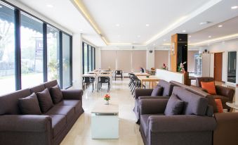 a modern living room with brown couches and chairs arranged around a coffee table , creating a cozy atmosphere at B2 Sriracha Premier Hotel