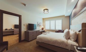 a modern bedroom with a large bed , dresser , and tv . the room is well - appointed and appears to be clean at Tailwater Lodge Altmar, Tapestry Collection by Hilton